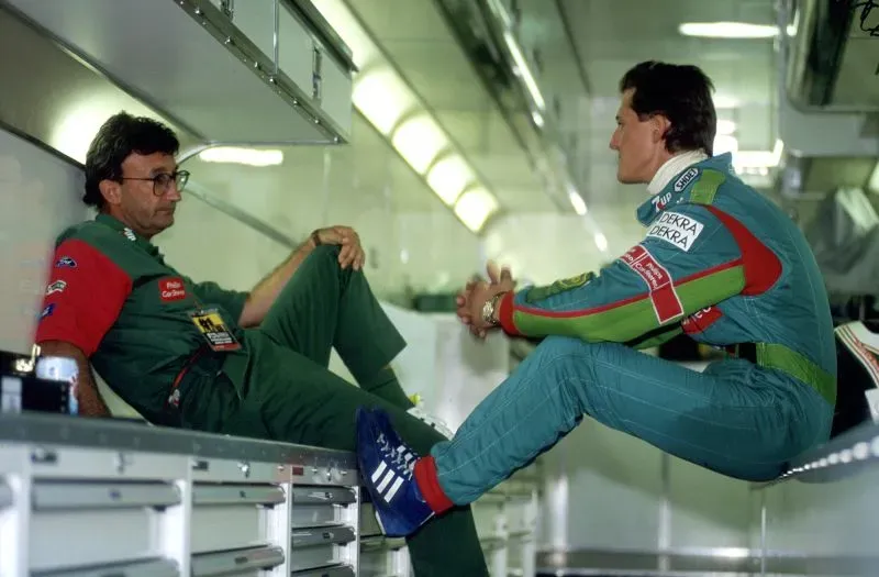 إيدي جوردان يتحدث مع مايكل شوماخر في حظيرة فريقه، مع التركيز على العلاقة بينهما وتأثير جوردان في عالم الفورمولا 1.