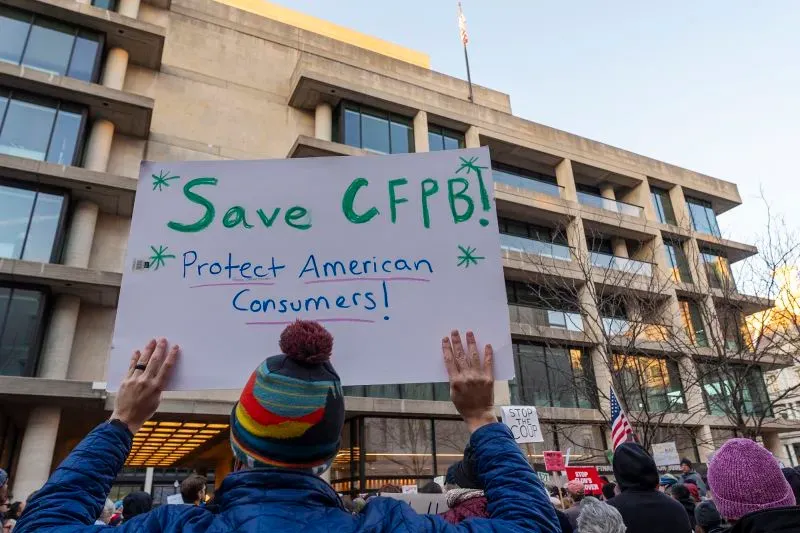 محتجون يحملون لافتة تطالب بحماية مكتب حماية المستهلك المالي (CFPB) أمام مبنى المكتب في واشنطن، مع التركيز على حقوق المستهلكين.