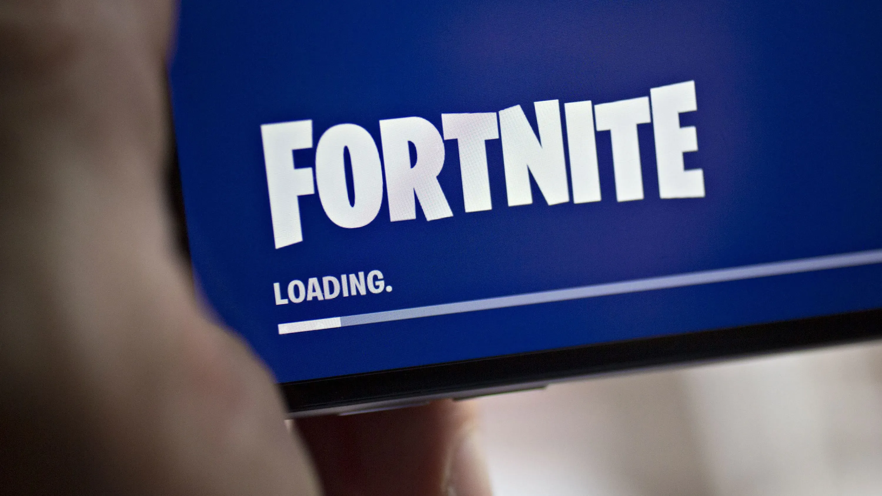 شاشة تحميل لعبة فورت نايت تظهر كلمة "فورت نايت" مع شريط تحميل، تعلن عن عودتها إلى متجر تطبيقات آبل بعد حظر دام خمس سنوات.