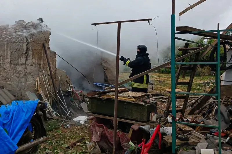 رجل إطفاء يوجه خرطوم المياه نحو حطام مبنى مدمر، وسط دخان كثيف، في منطقة تعرضت للقصف في أوكرانيا.