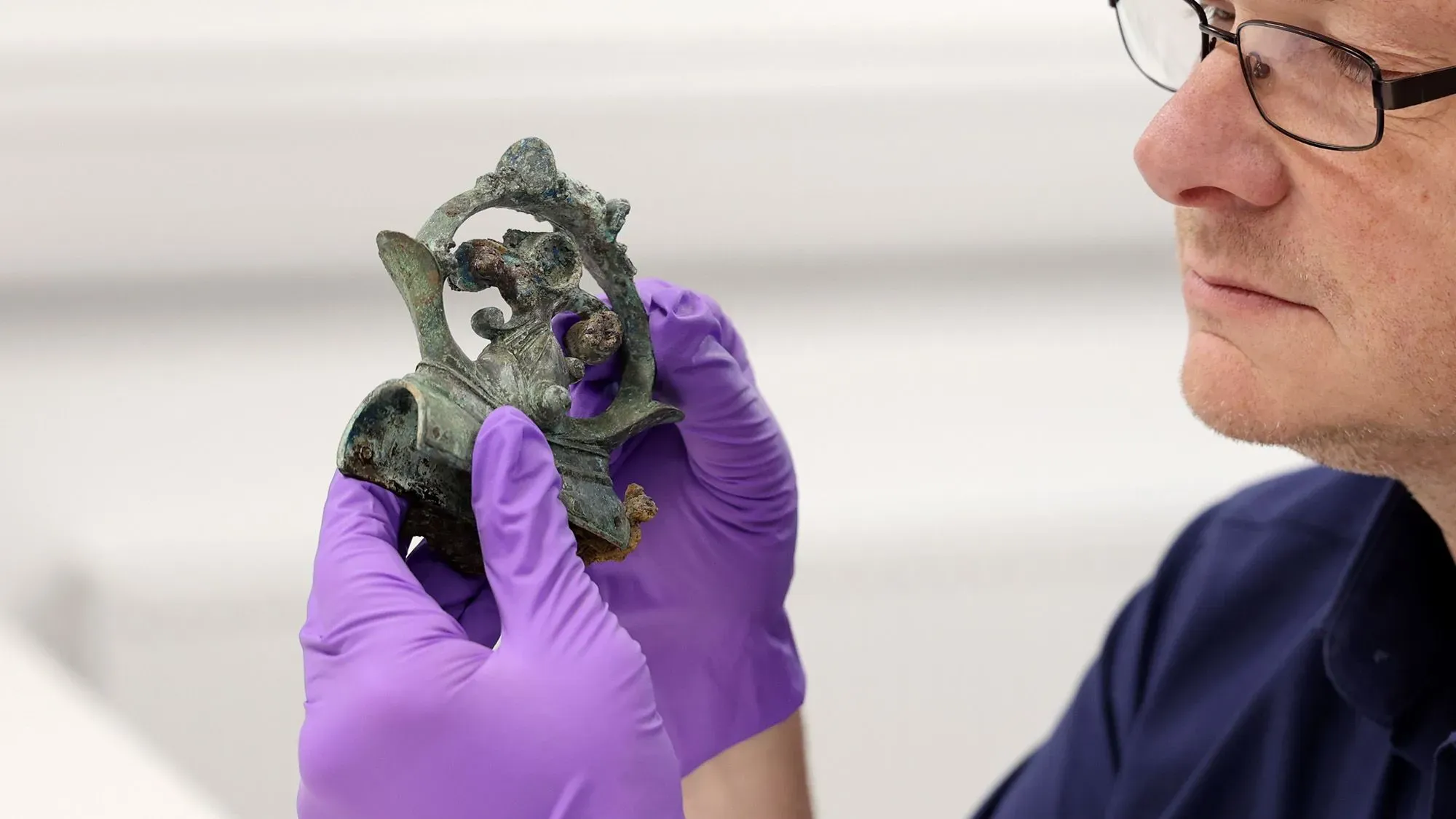 اكتشاف قطعة أثرية من العصر الحديدي تُظهر تفاصيل دقيقة، حيث يقوم باحث بفحصها بعناية، مما يعكس أهمية الكنز التاريخي في فهم الحياة القديمة في بريطانيا.