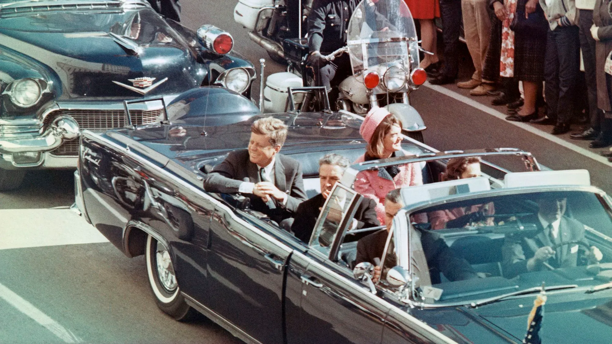 جون كينيدي وزوجته جاكلين في سيارة ليموزين خلال موكب في دالاس، قبل اغتياله في 22 نوفمبر 1963.