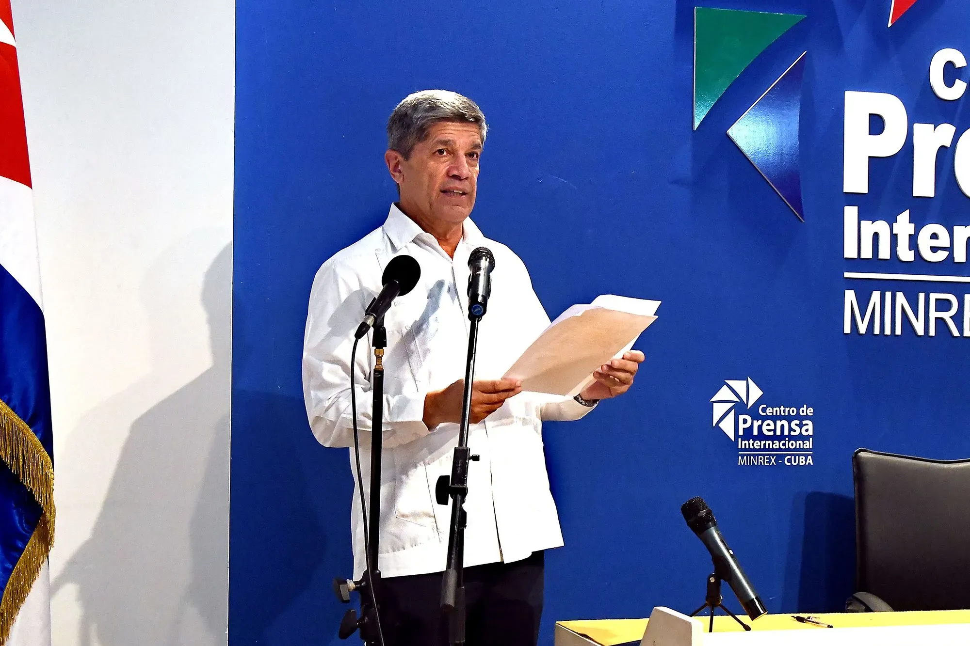 رجل يتحدث في مؤتمر صحفي في كوبا، مع وجود علم كوبا خلفه، وسط أجواء توتر بعد تبادل إطلاق النار بين جنود كوبيين وطاقم قارب.