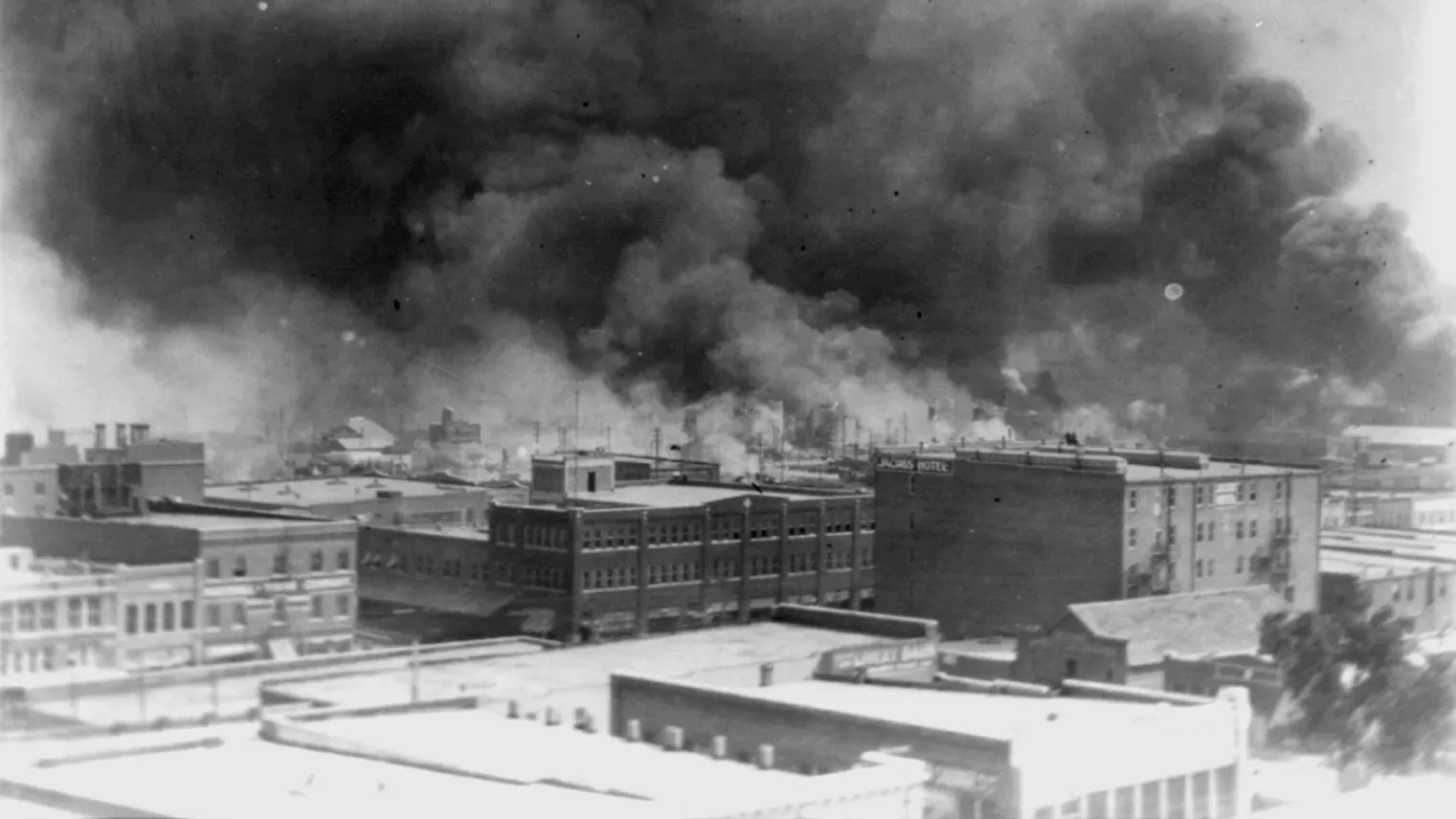 دخان كثيف يتصاعد فوق المباني في منطقة غرينوود بتولسا، بعد مذبحة 1921، التي أسفرت عن دمار واسع النطاق ومئات القتلى.