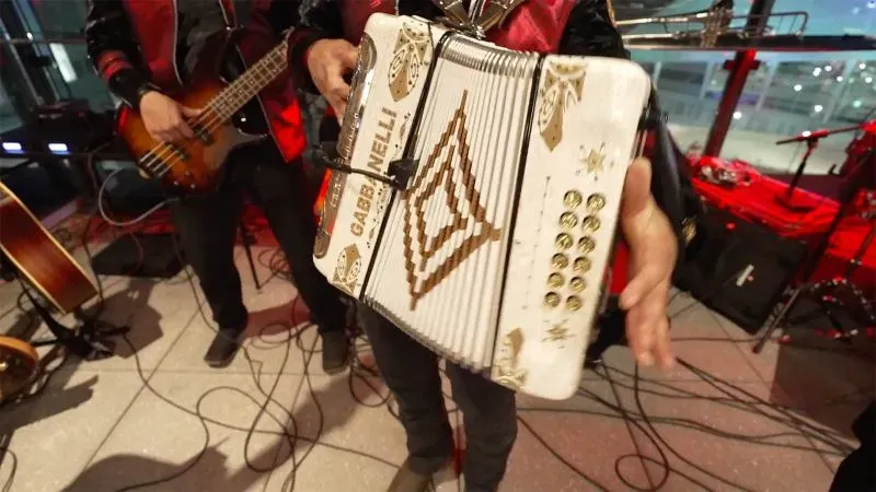 آلة الأكورديون تُعزف في حانة على السطح بأتلانتا، حيث تؤدي فرقة موسيقية أغاني تعكس ثقافة الموسيقى المكسيكية.