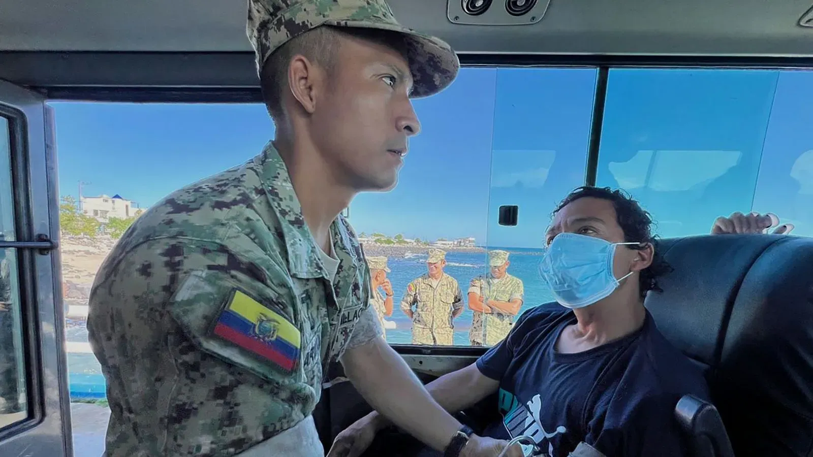 جنود إكوادوريون يتحدثون مع صياد تم إنقاذه بعد 55 يومًا في البحر، مع خلفية لجزر غالاباغوس.