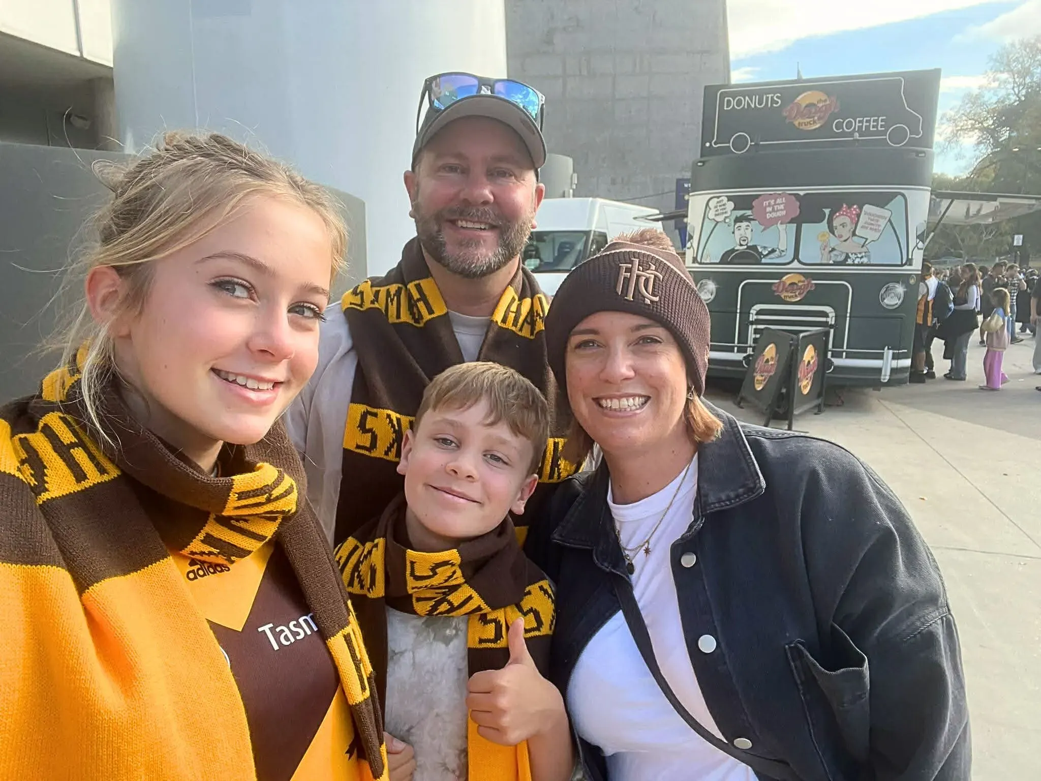 عائلة ثورن تتجمع في حدث عائلي، حيث يرتدي الأطفال وشاحين ويبتسمون، مع شاحنة طعام في الخلفية. تعكس الصورة شعور المغامرة والانتقال إلى أستراليا.