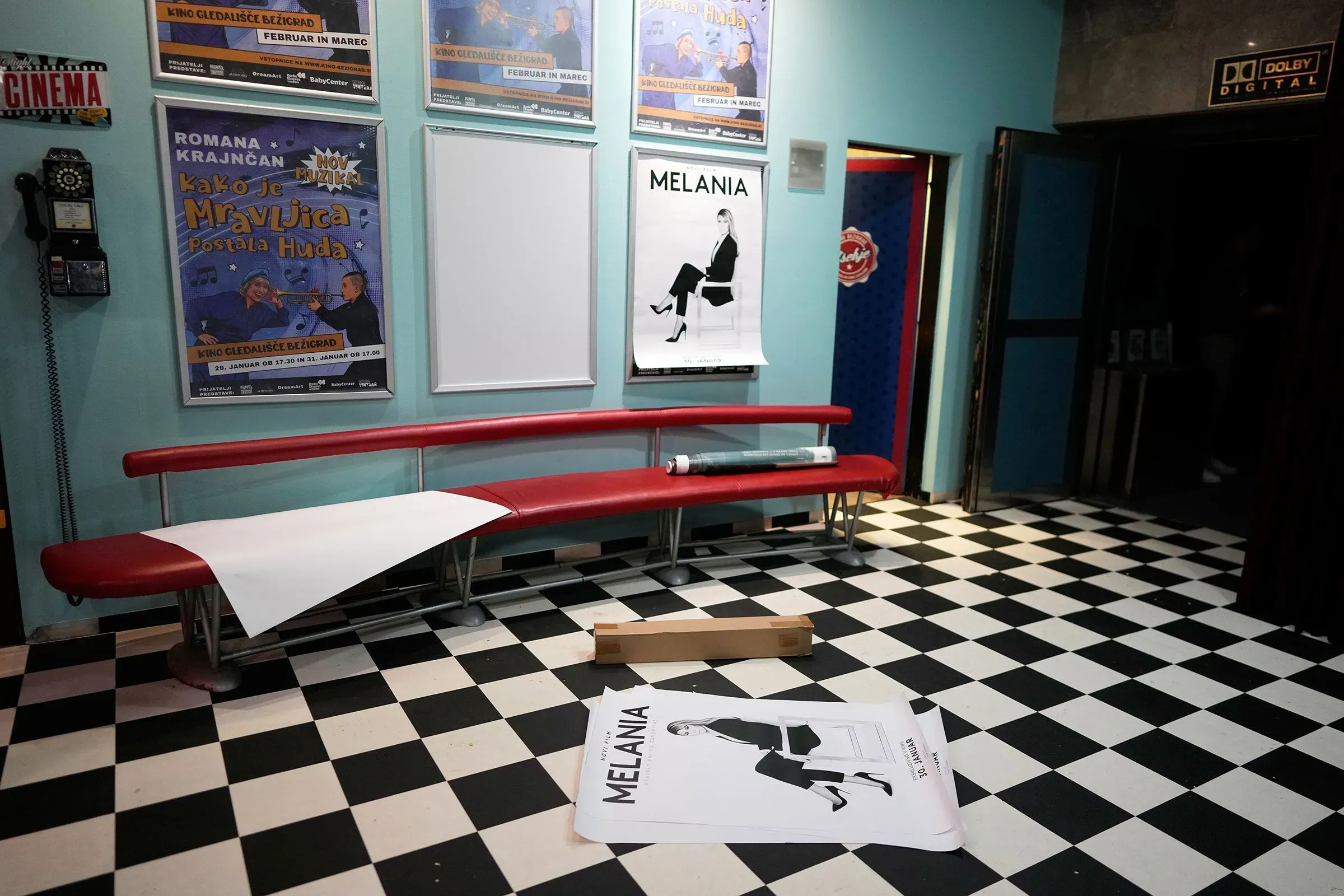 صورة لقاعة سينما تحتوي على مقاعد حمراء وملصق لفيلم "ميلانيا" على الحائط، مما يعكس أجواء عرض الفيلم الوثائقي.