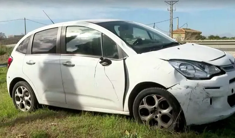 سيارة بيضاء متضررة على جانب الطريق، تمثل حادثة تصادم مع مجموعة من راكبي الدراجات في مايوركا، مما أدى لإصابة عدد منهم بجروح.