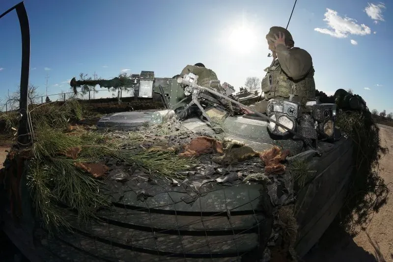 جندي ألماني يتواصل عبر جهاز اتصال على دبابة مموهة بالأشجار، في سياق تدريبات عسكرية مع حلفاء الناتو وسط ألمانيا.