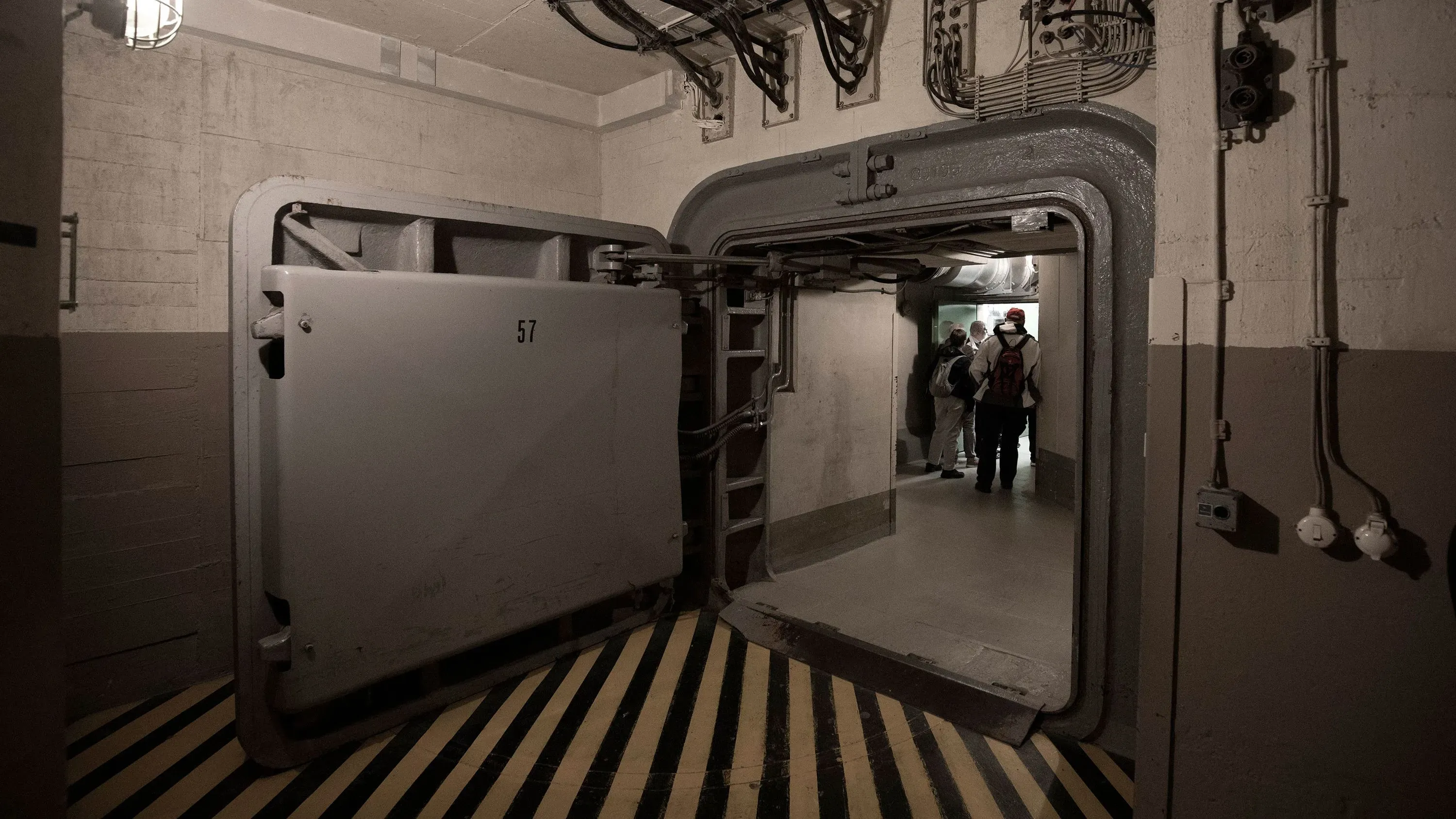 مدخل ملجأ محصن في ألمانيا، يظهر مجموعة من الأشخاص داخل المرفق، مما يعكس الحاجة الملحة لتحديث شبكة المخابئ في البلاد.