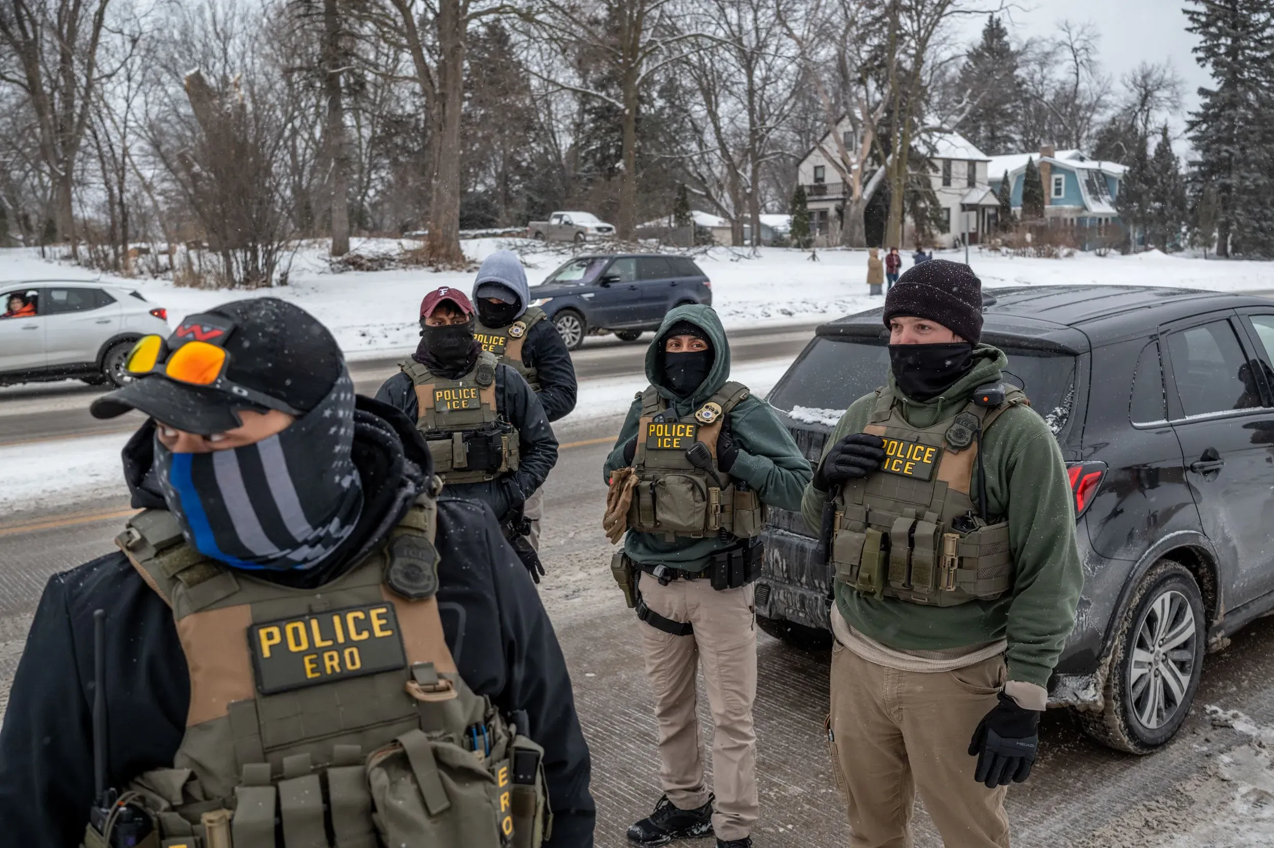 رجال أمن مسلحون يرتدون سترات مكتوب عليها "شرطة ICE" في منطقة مغطاة بالثلوج، وسط أجواء شتوية قاسية في مينيسوتا.