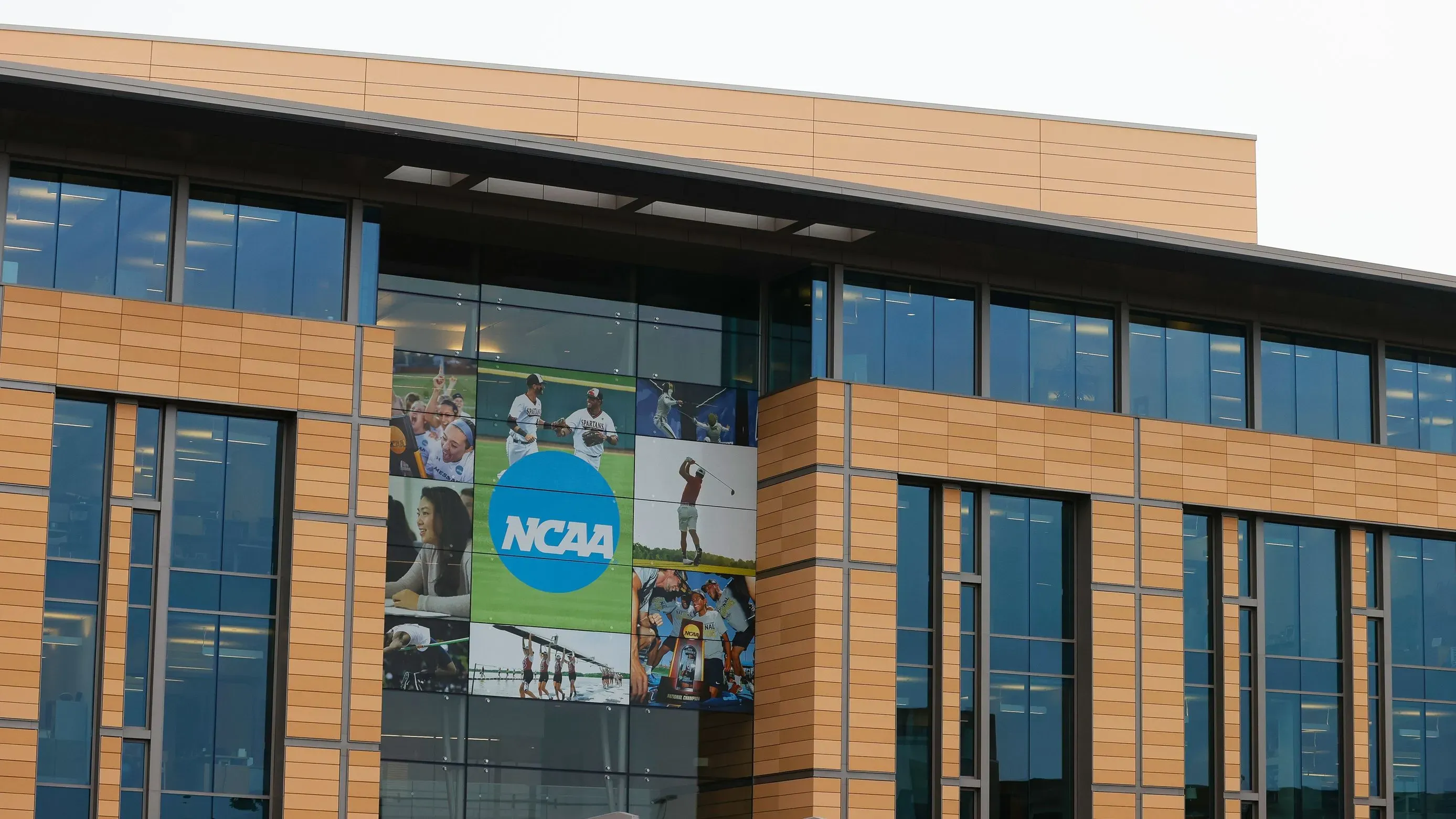 مبنى الرابطة الوطنية لرياضة الجامعات (NCAA) مع لافتة كبيرة تحمل شعار الرابطة، يرمز إلى التغييرات الجديدة في قوانين الرياضة الجامعية.