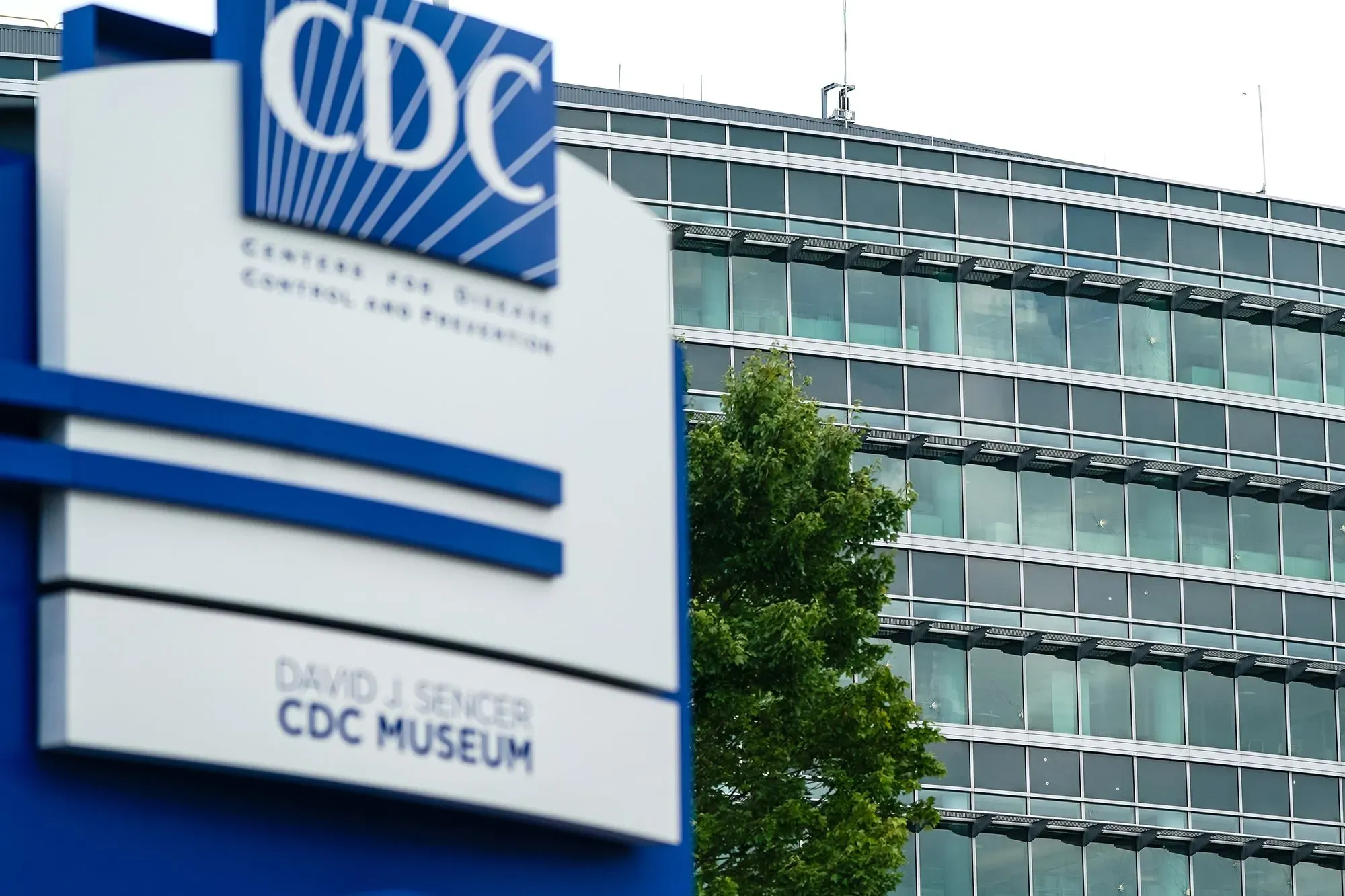 مبنى مركز السيطرة على الأمراض والوقاية منها (CDC) مع لافتة المتحف، يظهر تصميمه العصري والنوافذ الزجاجية الكبيرة.