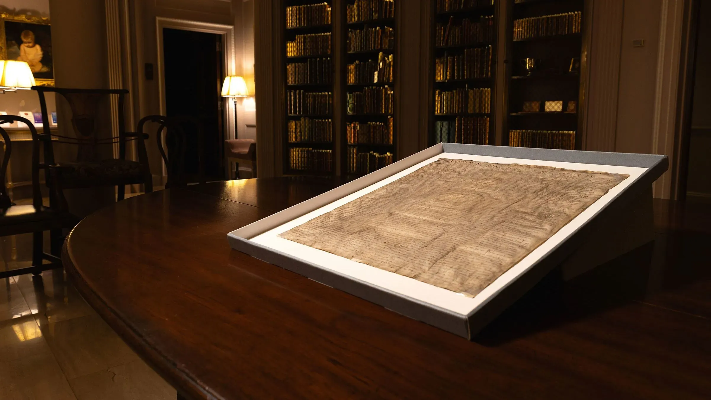 نسخة نادرة من الماغنا كارتا عام 1300 موضوعة على طاولة في مكتبة كلية الحقوق بجامعة هارفارد، محاطة بأرفف كتب.