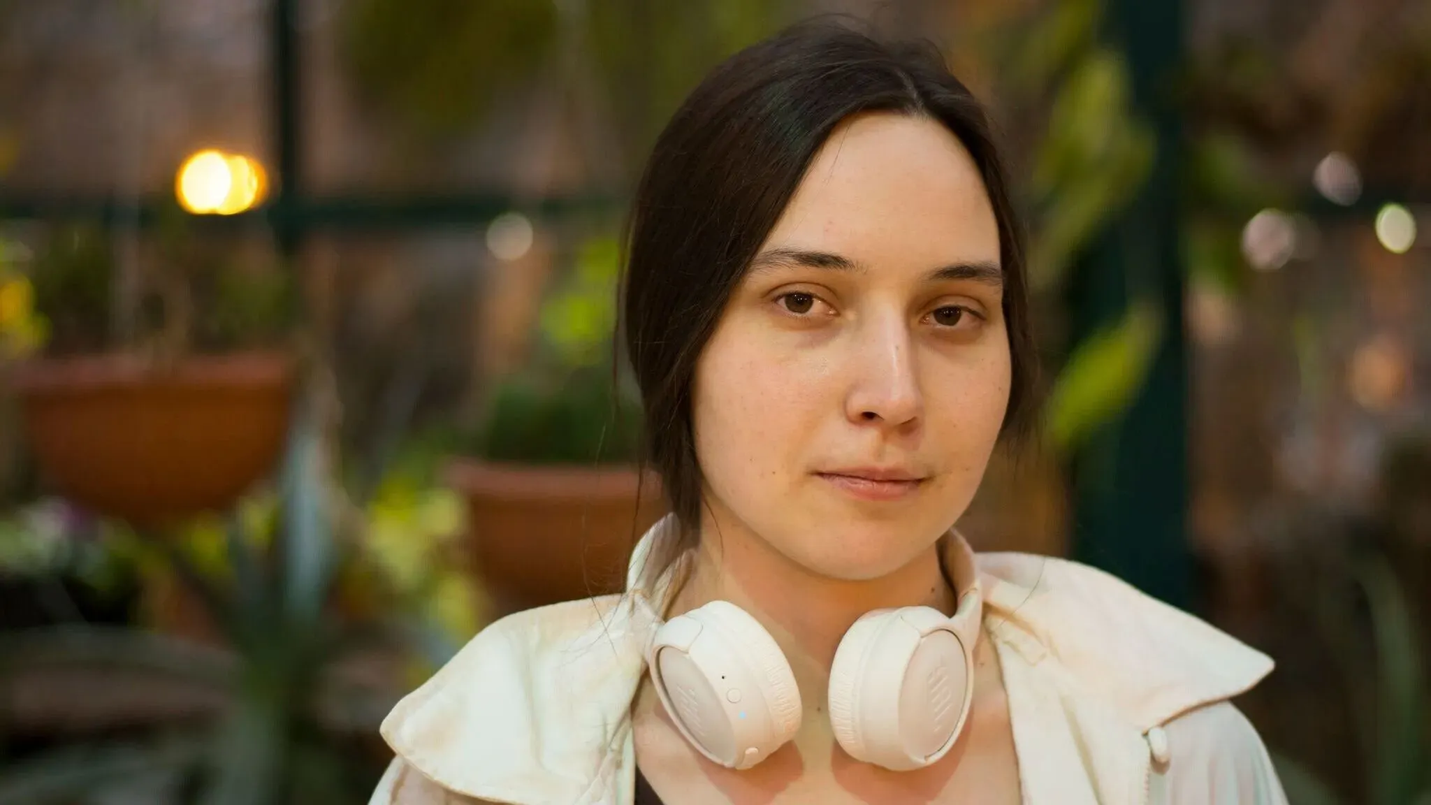 كسينيا بيتروفا، العالمة الروسية المحتجزة في مركز الهجرة، تظهر في صورة أثناء محادثة فيديو، مع سماعات رأس، في بيئة مزدحمة.