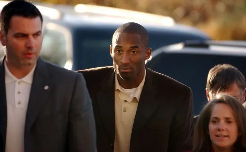 كوبي براينت يتوجه إلى المحكمة مع فريقه القانوني، مع تعبير جدّي على وجهه، وسط أجواء مشحونة بالضغوط الإعلامية حول قضيته.