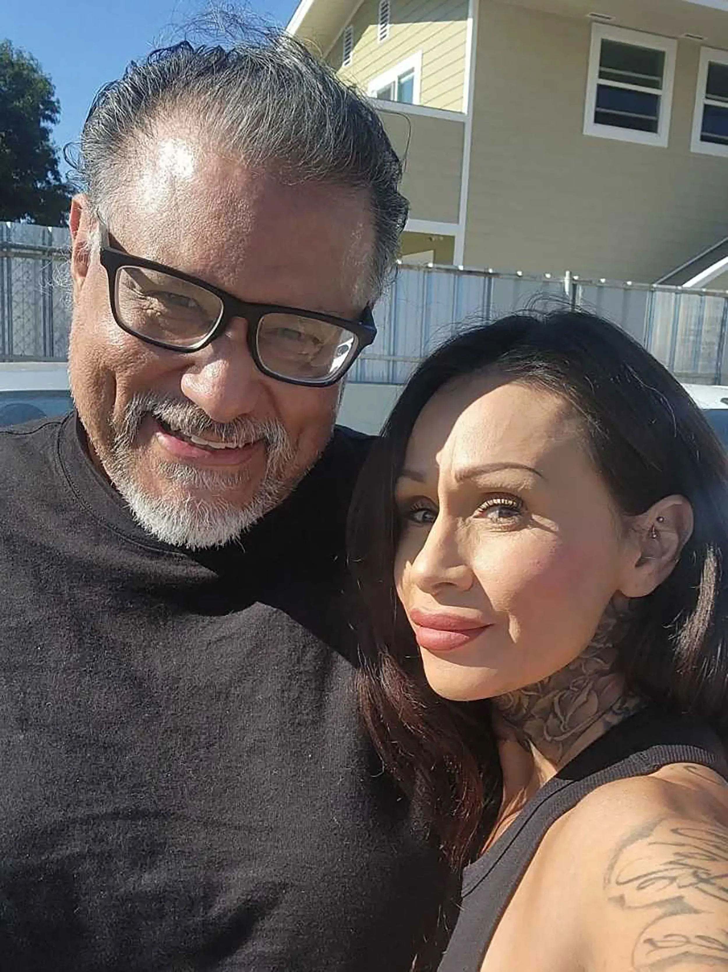 صورة لجوي لويا مع امرأة، كلاهما يبتسم، في بيئة خارجية مشمسة. تعكس الصورة لحظة من الألفة بينهما بعد عقود من التحديات.