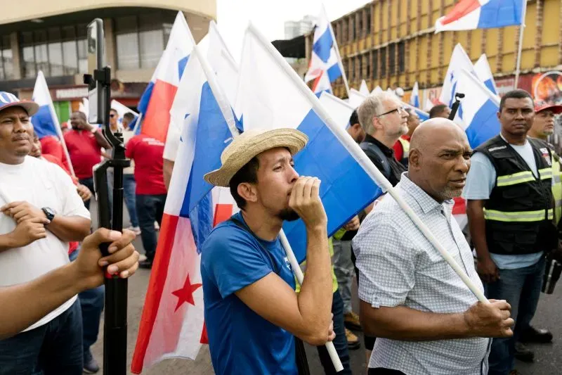 محتجون يحملون أعلام بنما في تظاهرة، مع التركيز على شاب يرتدي قبعة ويعبر عن مشاعره، مما يعكس القضايا السياسية الجارية.