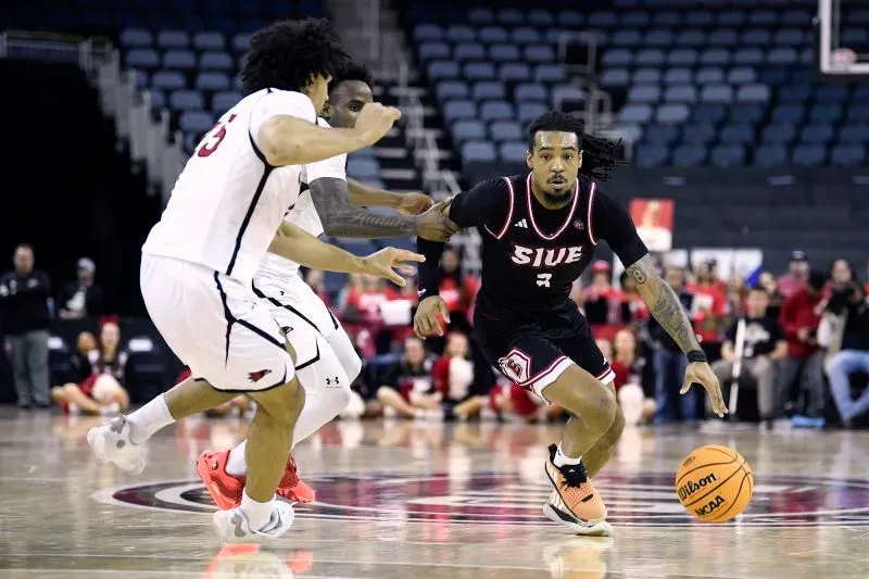 لاعب كرة سلة من فريق جامعة جنوب إلينوي إدواردزفيل (SIUE) يتقدم بالكرة خلال مباراة حاسمة، وسط منافسة قوية من لاعبي الفريق المنافس.