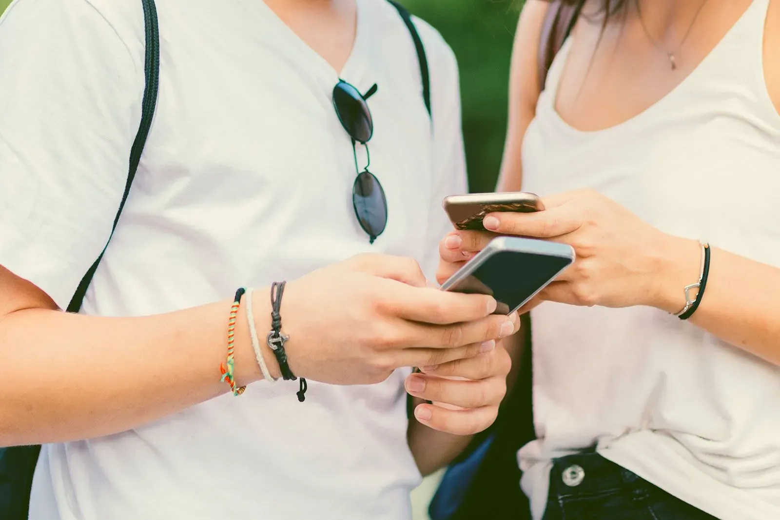 شخصان مراهقان يحملان هواتف ذكية، يتفاعلان مع بعضهما عبر تطبيقات التواصل، مما يبرز مخاطر استخدام المراهقين لتطبيقات المواعدة.