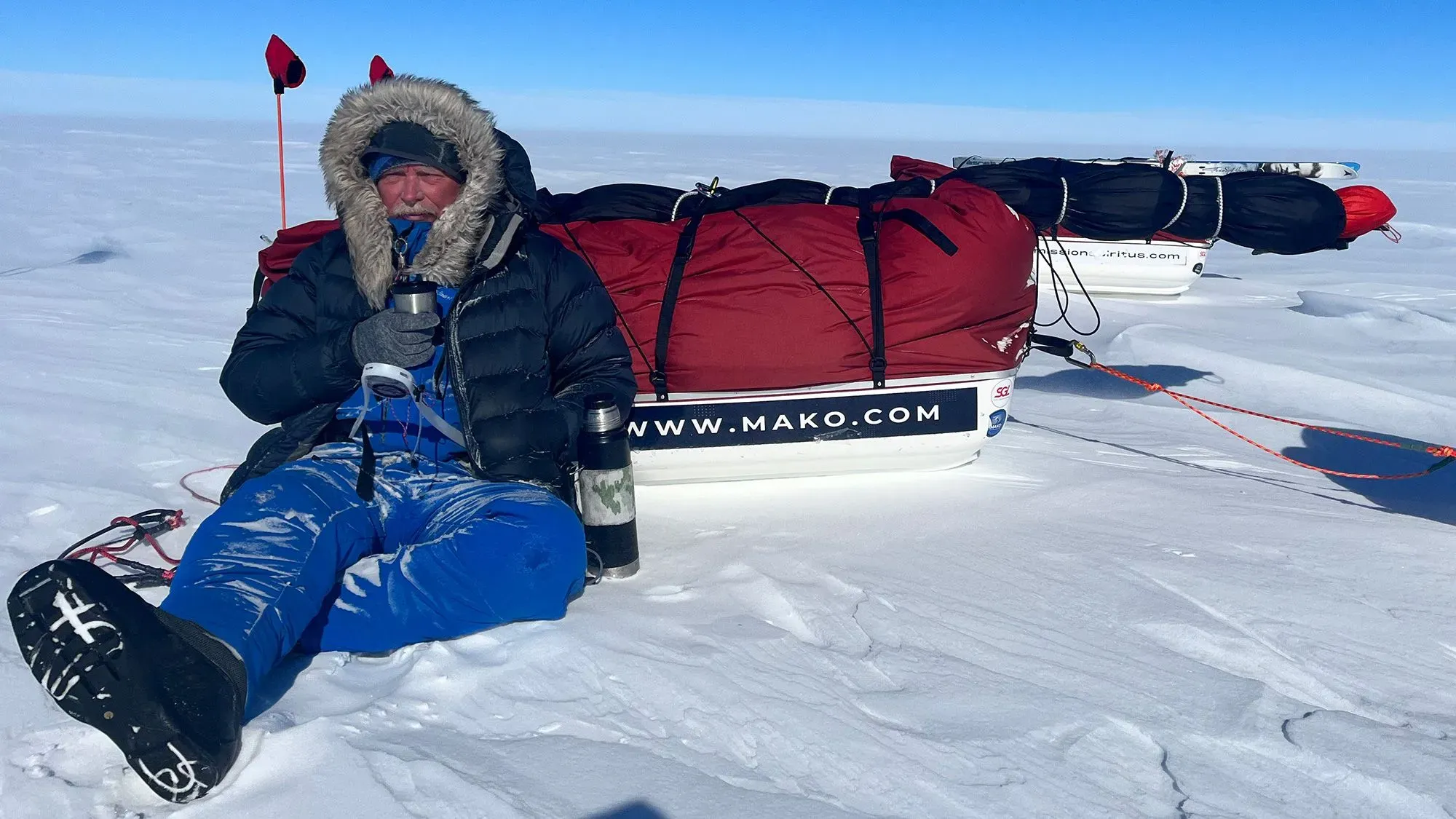 يظهر المستكشف آلان تشامبرز جالساً على الثلج في القارة القطبية الجنوبية، محاطاً بزلاجات محملة بالمؤن والمعدات، خلال رحلة بحث عن اللدائن الدقيقة.