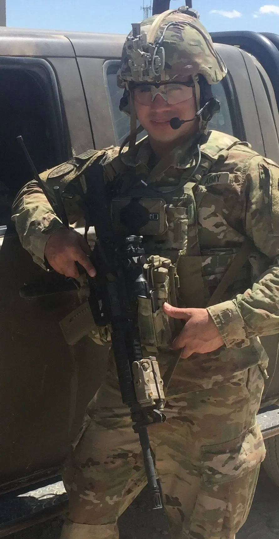 سعيد نور، قدامى المحاربين في الجيش الأمريكي، يقف بجانب مركبة عسكرية، حاملاً سلاحه، في سياق قضيته المتعلقة بشقيقه الأفغاني المحتجز.