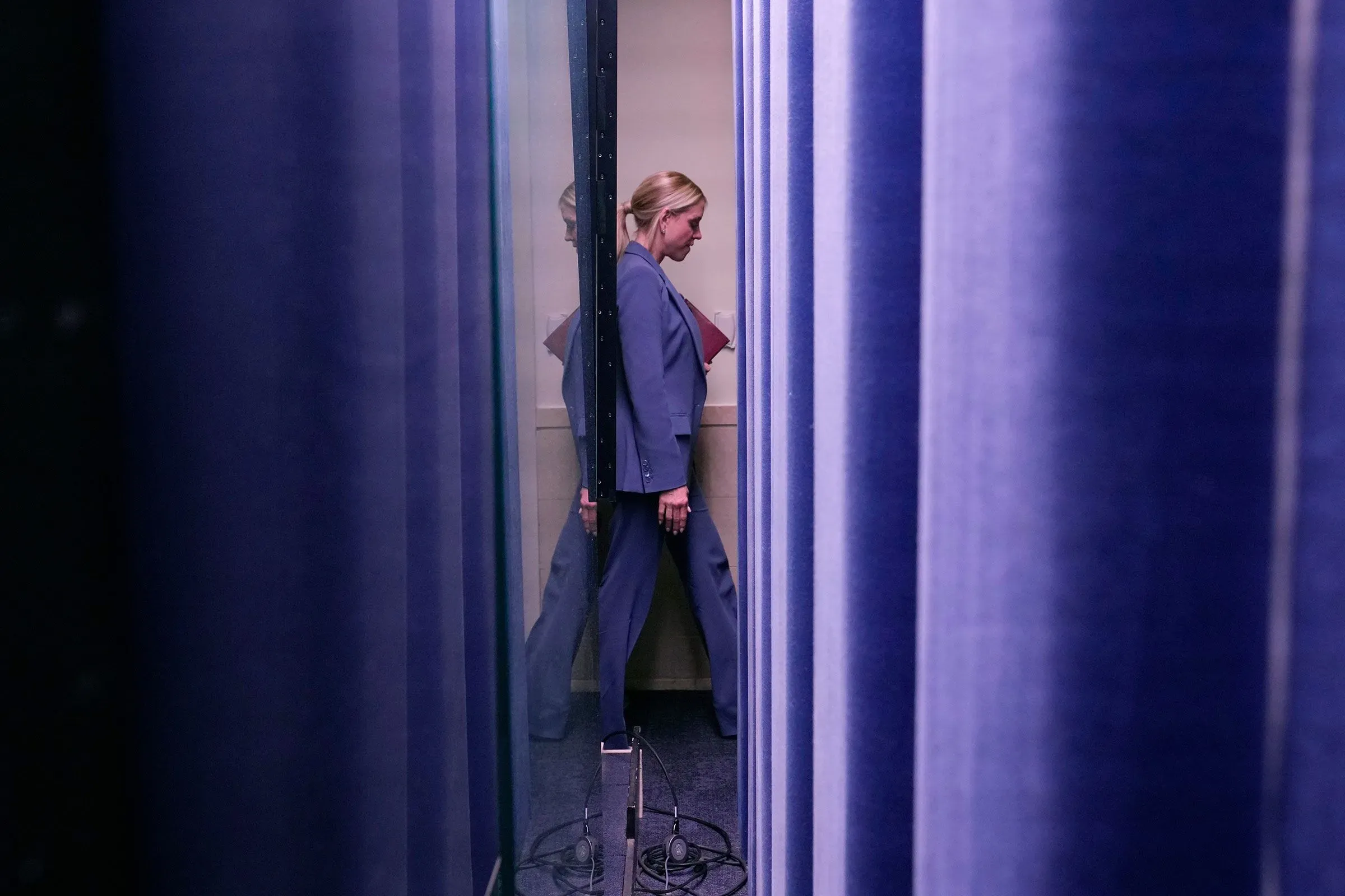 امرأة ترتدي بدلة رسمية تسير بين ستائر زرقاء، في سياق استدعائها للإدلاء بشهادتها حول قضية جيفري إبشتاين في مجلس النواب.