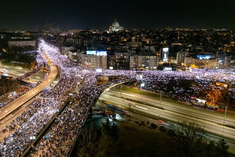 مظاهرة حاشدة في بلغراد ليلاً، حيث تجمع الآلاف من المتظاهرين حاملين الأضواء، تعبيراً عن الغضب تجاه الحكومة بعد انهيار مظلة محطة نوفي ساد.