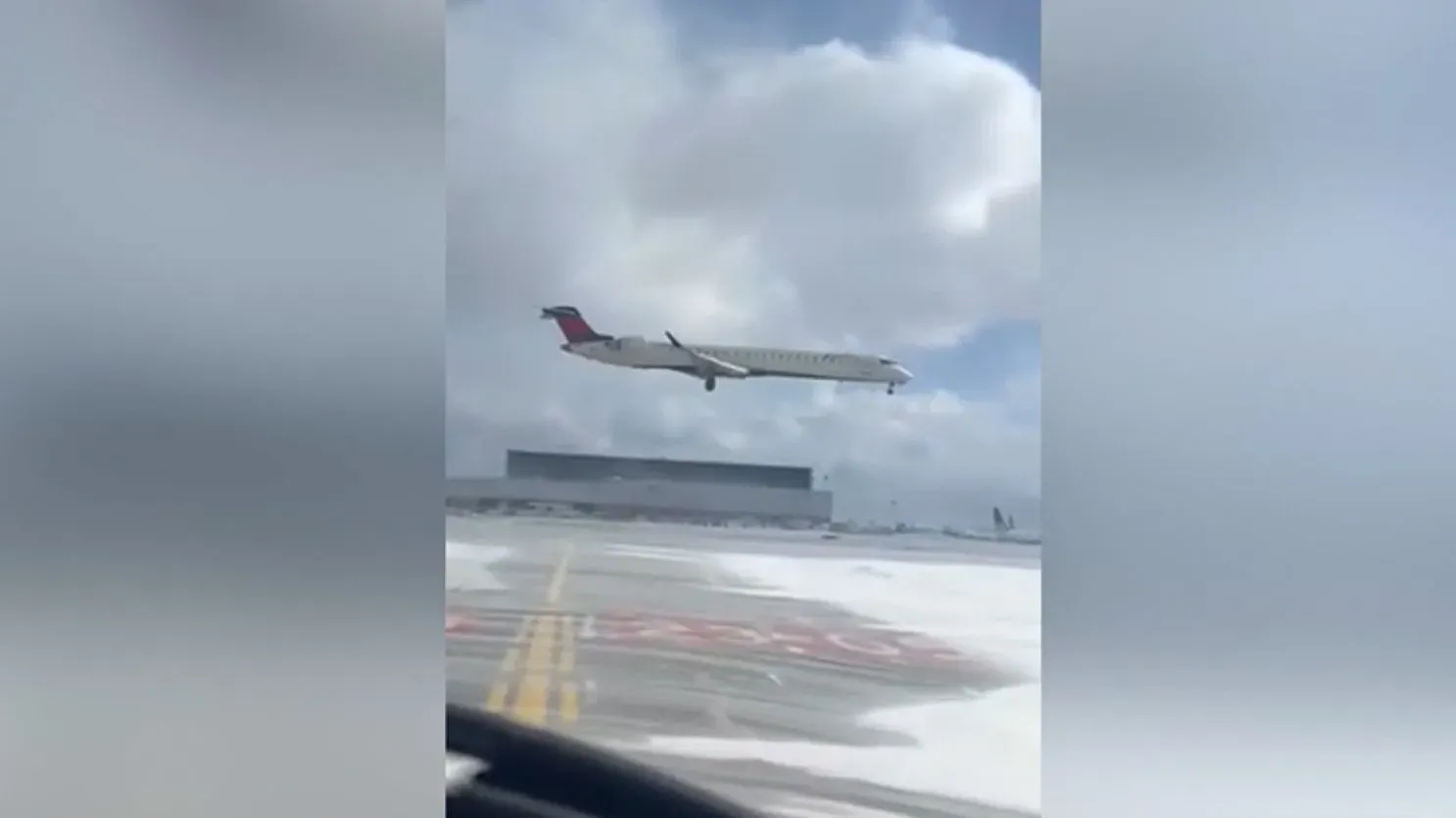 طائرة بومباردييه CRJ900 مقلوبة رأساً على عقب بعد حادث تحطم في مطار تورونتو، مع وجود دخان يخرج من جناحها المكسور.
