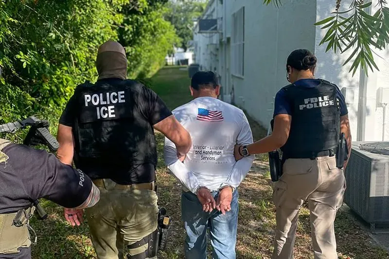 عملية اعتقال لمهاجر تحت إشراف ضباط من وكالة إنفاذ قوانين الهجرة والجمارك، مع التركيز على إجراءات إنفاذ قوانين الهجرة.