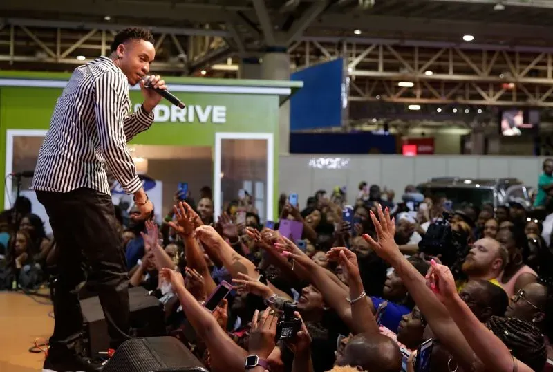 روتيمي يؤدي على المسرح أمام جمهور متحمس، حيث تتجه الأيادي نحو الفنان بينما يلتقط الحضور الصور.