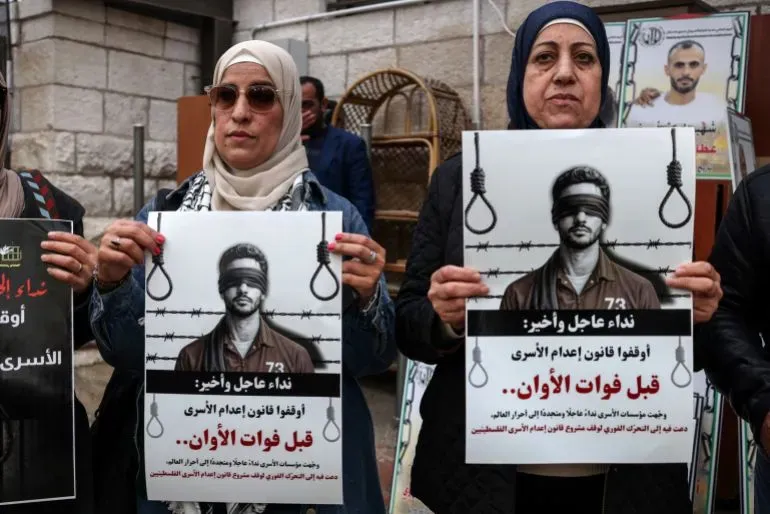 نساء يحملن لافتات تندد بقانون الإعدام ضد الأسرى الفلسطينيين، خلال مظاهرة في الضفة الغربية، تعبيرًا عن الاحتجاج والمطالبة بحقوق الأسرى.