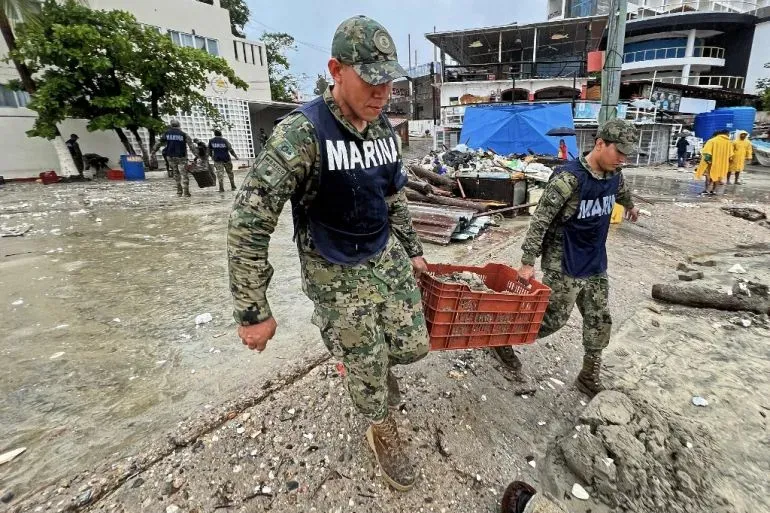 جنود يحملون صناديق أثناء جهود الإغاثة في أكابولكو بعد إعصار إيريك، حيث تتواجد أنقاض ومياه الفيضانات في الشوارع.