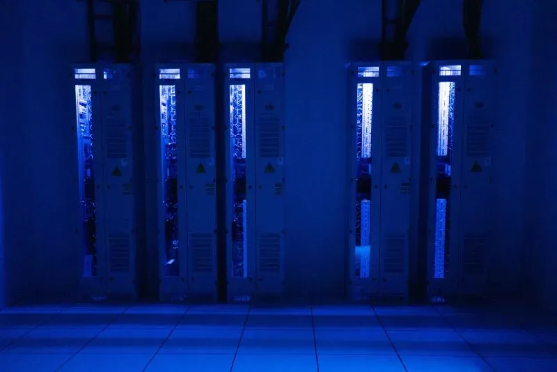 غرفة تحتوي على عدة خوادم مضاءة باللون الأزرق، تمثل بيئة تكنولوجيا المعلومات المستخدمة في مكافحة الاحتيال عبر الإنترنت.