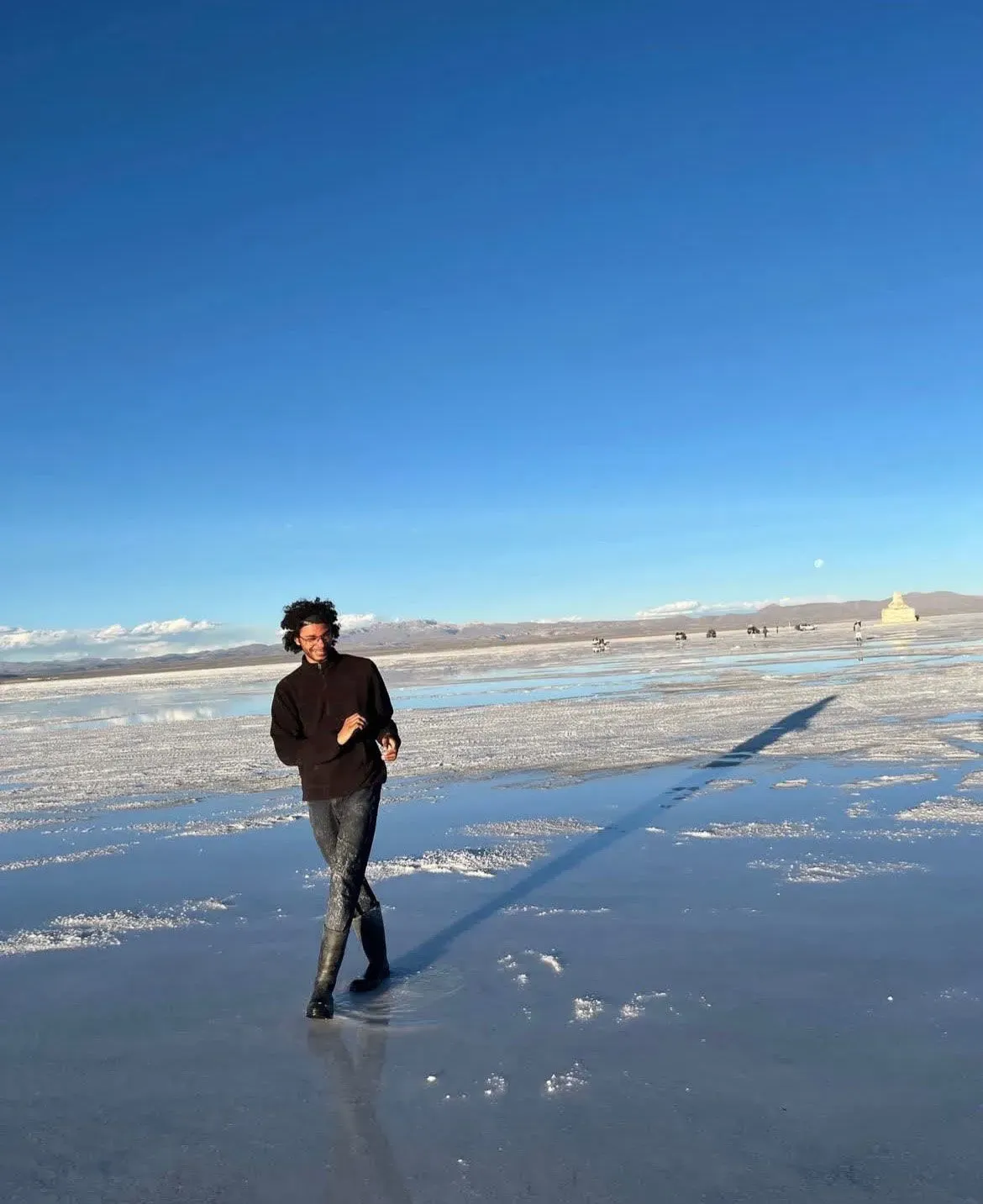 شاب يسير على سطح مائي في منطقة صحراوية، مع سماء زرقاء صافية في الخلفية، يعكس روح المغامرة والحرية بعد تجربة احتجاز صعبة في فنزويلا.