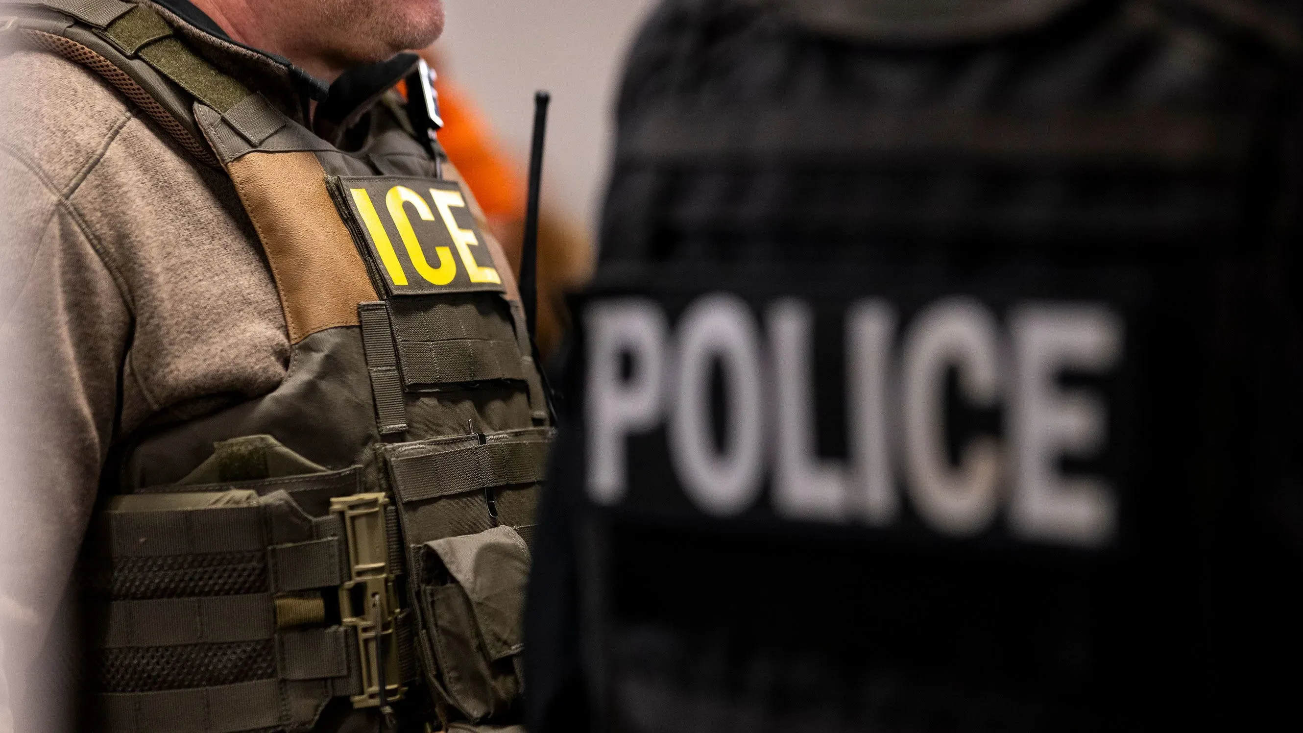 عميل من إدارة الهجرة والجمارك يرتدي سترة واقية تحمل كلمة "ICE" أثناء اعتقاله في محكمة بوسطن، مما يعكس التوترات القانونية حول الاعتقالات في المحاكم.