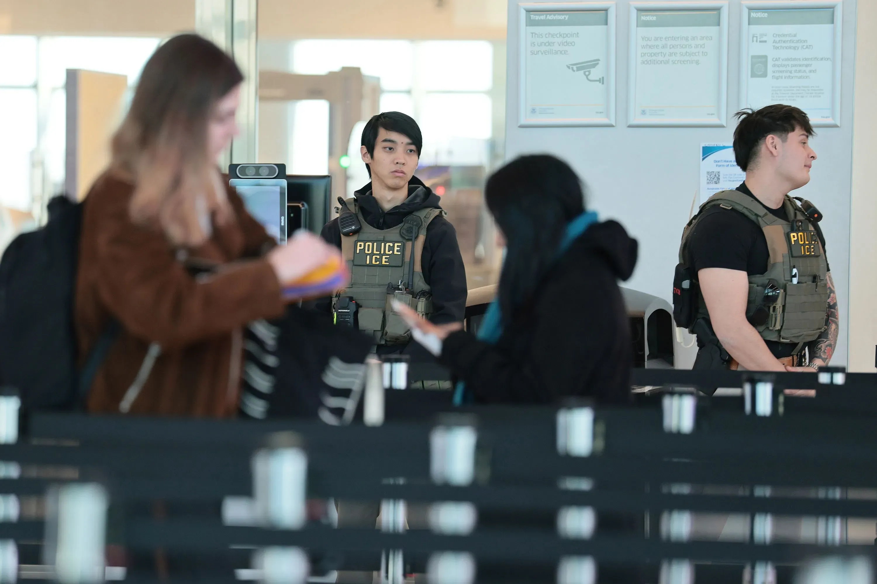 وجود عملاء من إدارة الهجرة والجمارك في مطار مزدحم، حيث يساعدون المسافرين في طوابير طويلة وسط أجواء من الارتباك.