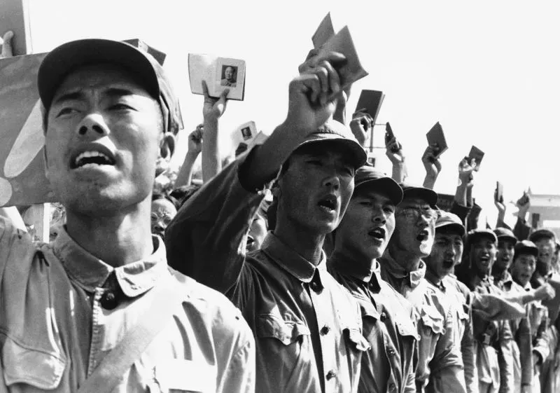 مجموعة من الشباب يرتدون ملابس عسكرية، يرفعون كتبًا وصورًا لماو تسي تونغ، ويهتفون في سياق الثورة الثقافية في الصين.