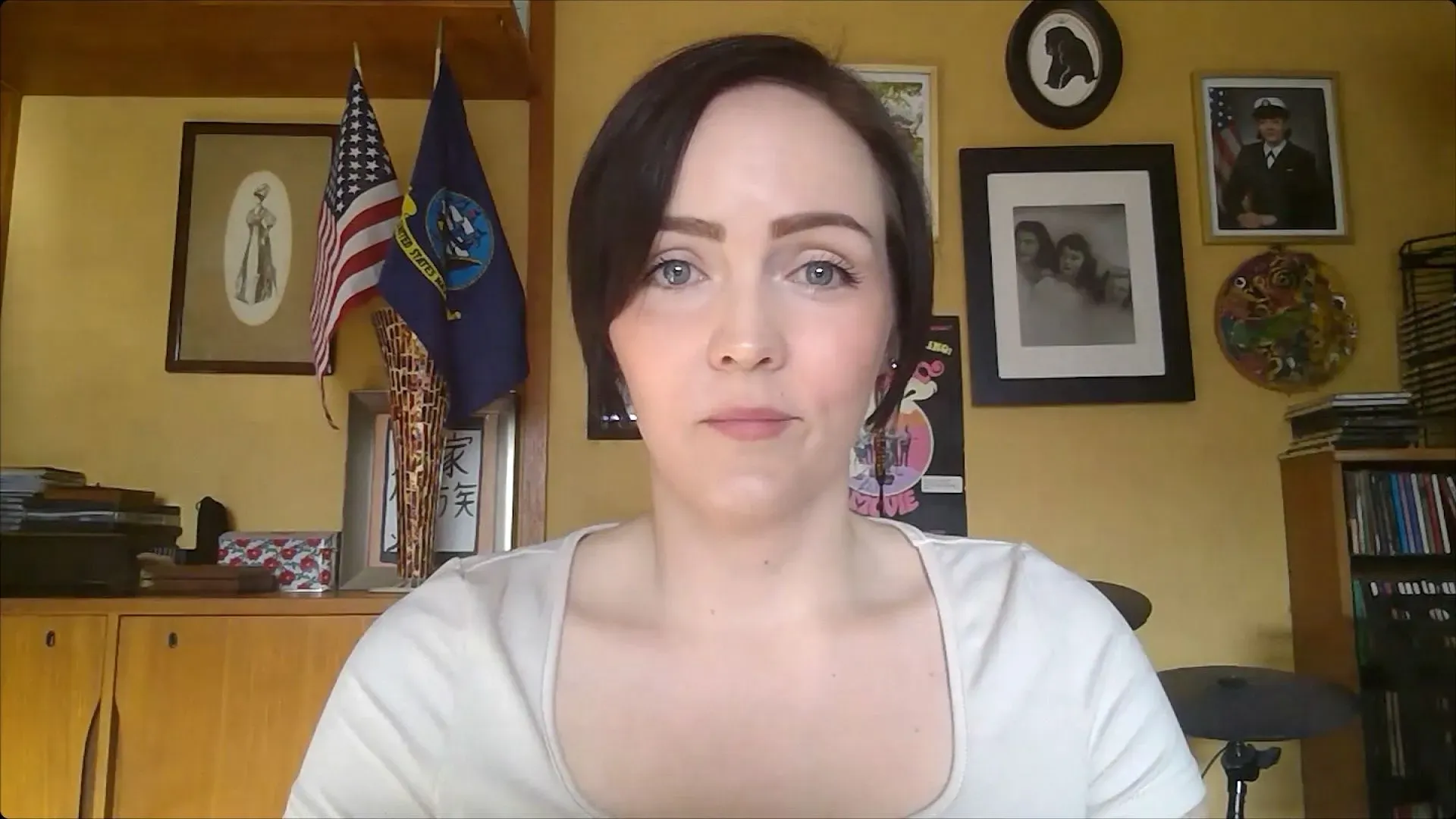 امرأة شابة تتوسط الصورة، تعبر عن القلق، مع العلم الأمريكي وعلم البحرية خلفها، تعكس تأثيرات فصل الموظفين الفيدراليين.