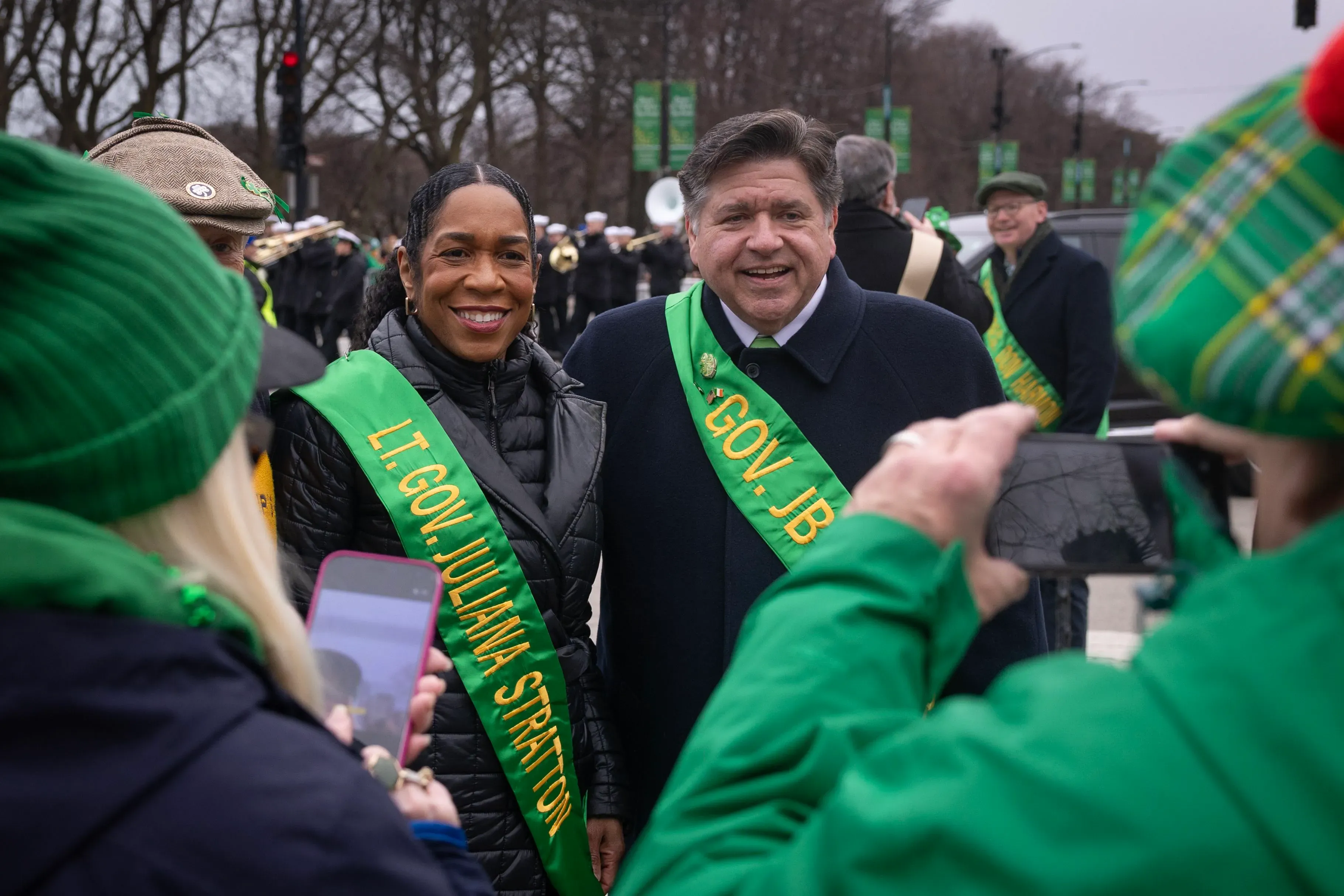 جوليانا ستراتون، نائبة حاكم إلينوي، مع الحاكم جي بي بريتزكر في احتفال، يرتديان شارات تحمل أسمائهما، وسط حشد من المؤيدين.