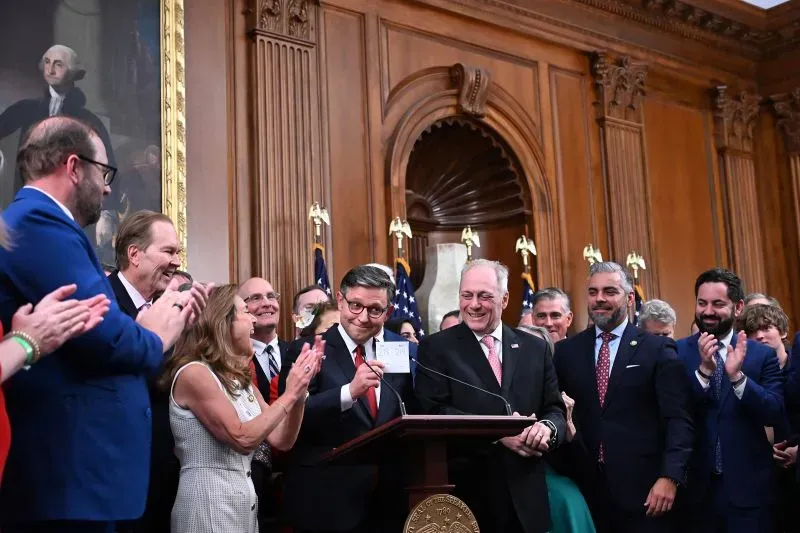 احتفال في قاعة مجلس النواب بعد تمرير مشروع قانون ترامب، حيث يظهر نواب يصفقون ويبتسمون، مع لافتة تشير إلى التصويت.