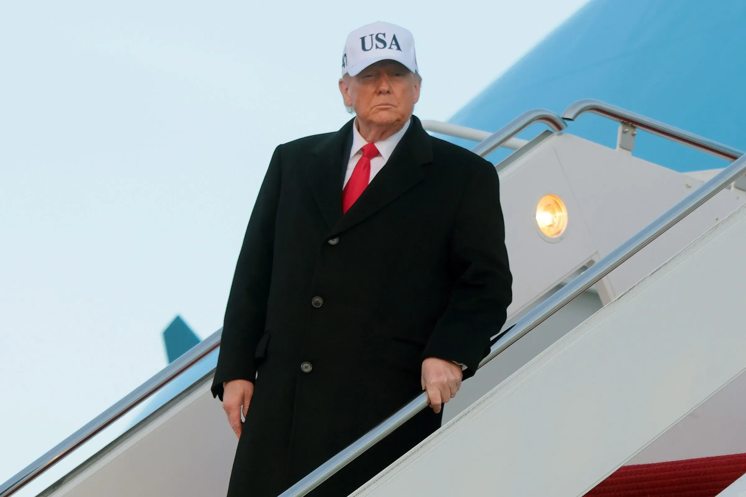 ترامب ينزل من الطائرة مرتديًا قبعة تحمل شعار "الولايات المتحدة الأمريكية"، مع تعبير جاد، في سياق تصريحاته حول غرينلاند.