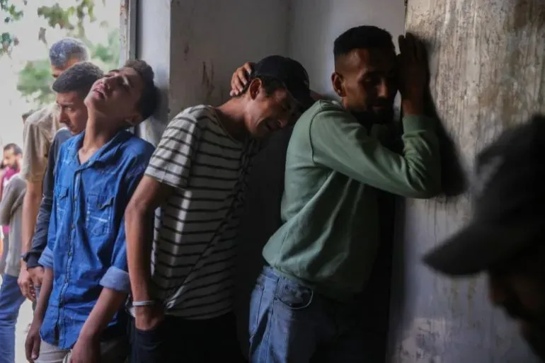 شبان فلسطينيون ينتظرون في طابور للحصول على المساعدات الغذائية في غزة، مع تعبيرات قلق على وجوههم بسبب الأوضاع الصعبة.