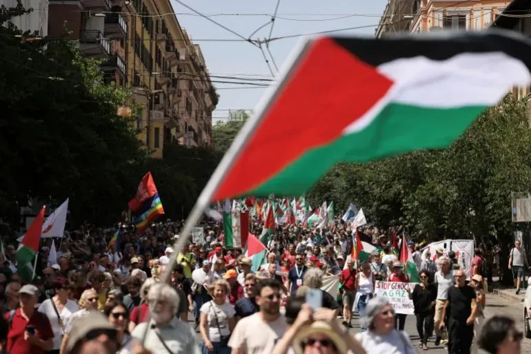 مظاهرة حاشدة في روما تأييدًا لفلسطين، حيث يحمل المتظاهرون الأعلام الفلسطينية ولافتات تطالب بإنهاء الحرب والجرائم ضد الفلسطينيين.