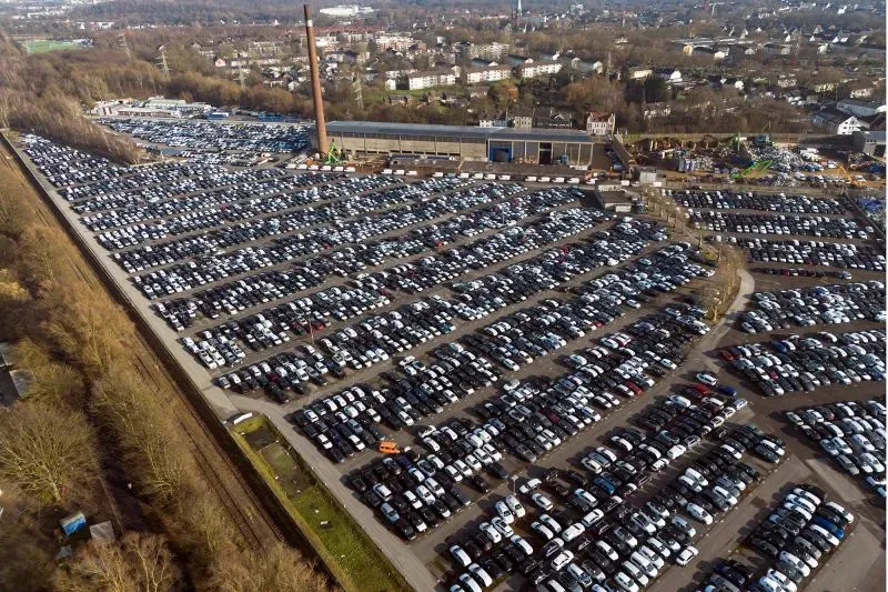 ساحة ضخمة مليئة بالسيارات الجديدة في ألمانيا، تعكس التحديات الاقتصادية الحالية وتأثيرها على صناعة السيارات.