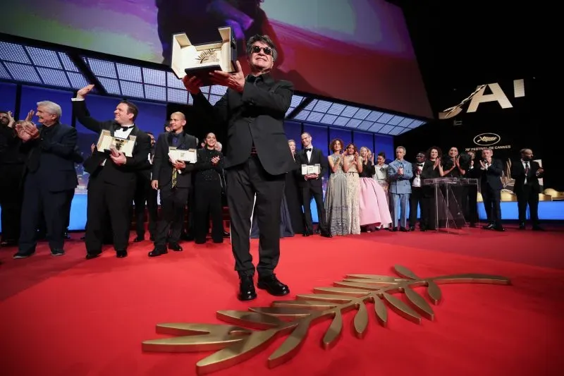 المخرج الإيراني جعفر بناهي يحمل جائزة السعفة الذهبية على السجادة الحمراء في مهرجان كان السينمائي، وسط تصفيق الحضور.