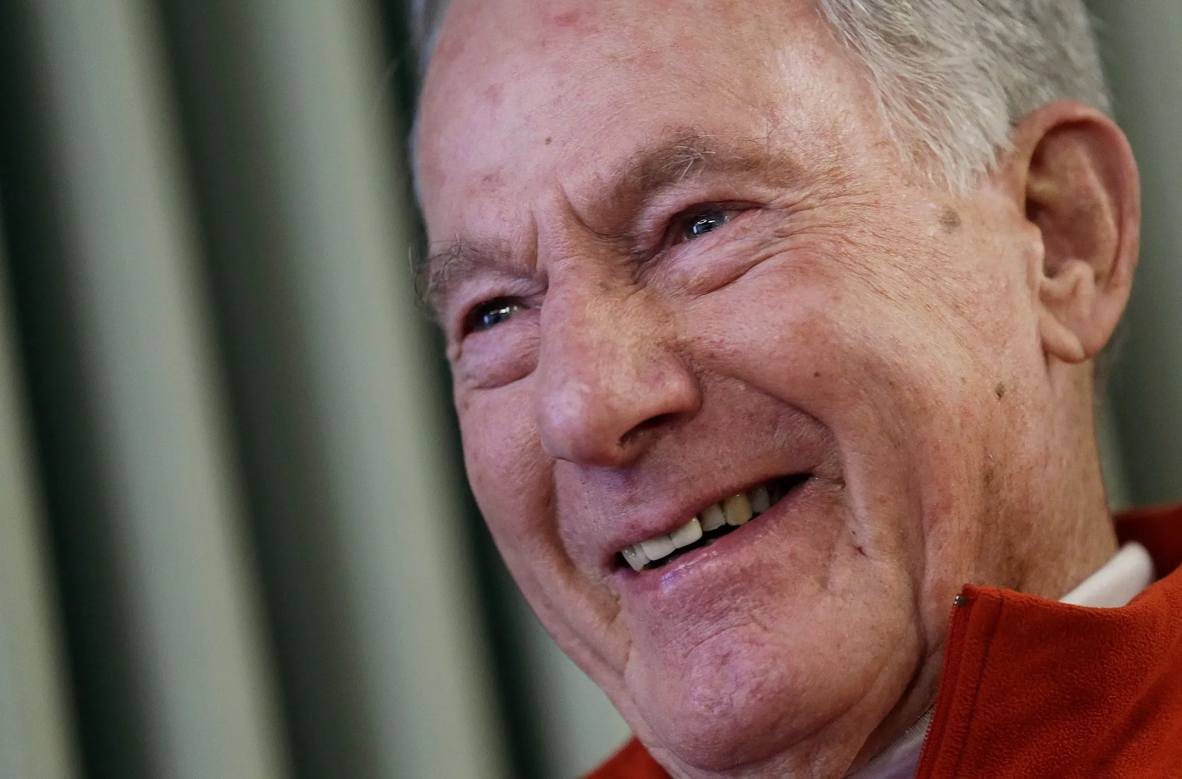 تظهر الصورة جيم ويتاكر، أول أمريكي يتسلق قمة جبل إيفرست، مبتسمًا في حديثه عن مغامراته في تسلق الجبال.