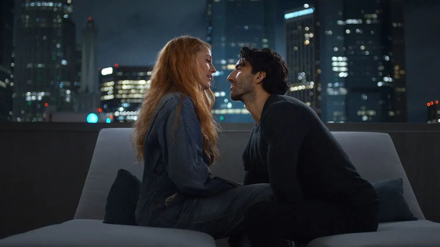 مشهد من فيلم "It Ends With Us" يظهر بليك ليفلي وجاستن بالدوني في لحظة عاطفية على خلفية مدينة مضاءة ليلاً، مما يعكس عمق علاقتهما.