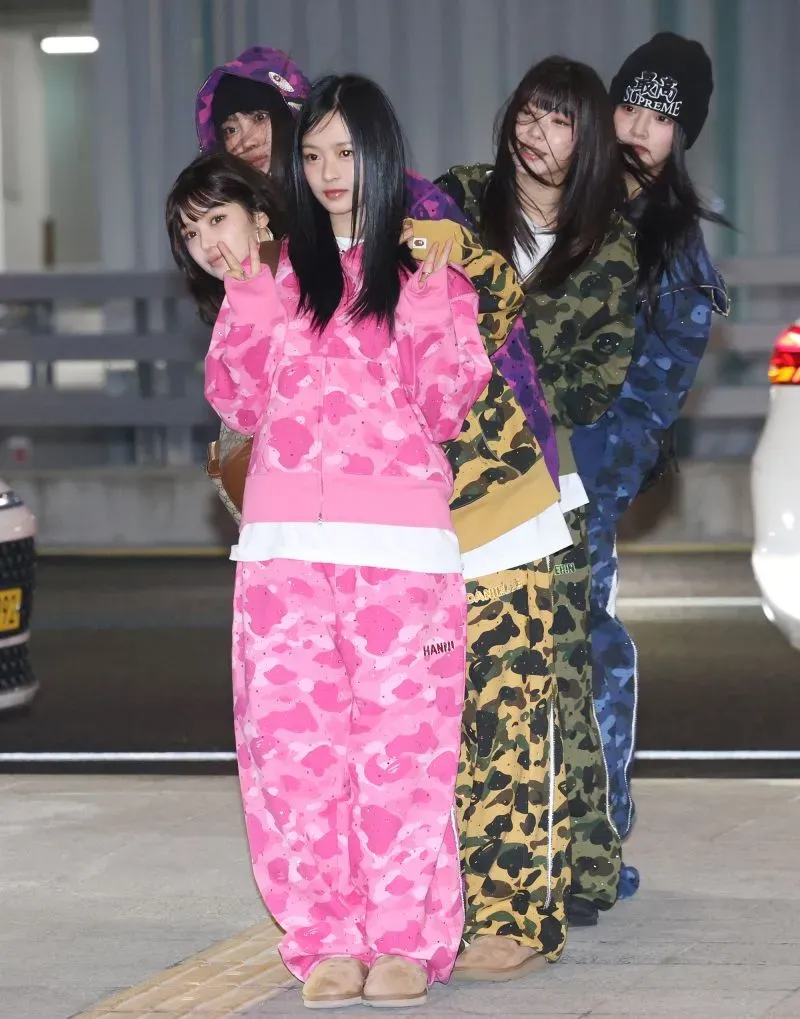 أعضاء فرقة NJZ يرتدون ملابس ملونة ويظهرون بتصميم عصري، مع التركيز على الأناقة والجرأة، وسط أجواء احتفالية.